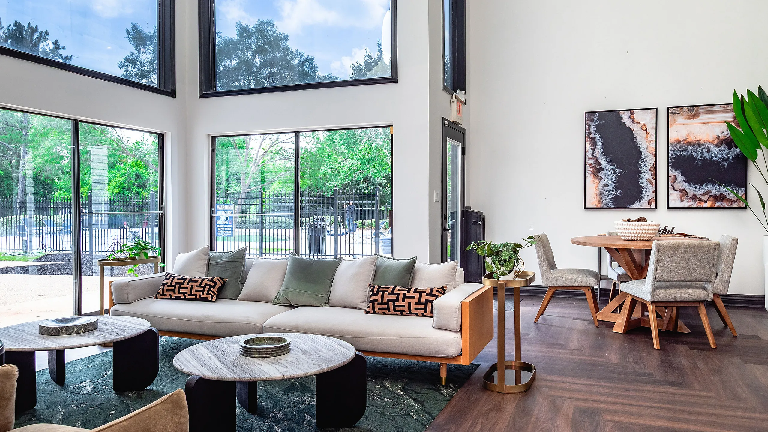Bright and inviting living area with large windows, stylish furniture, and modern decor, featuring comfortable seating and a chic dining space with nature views.