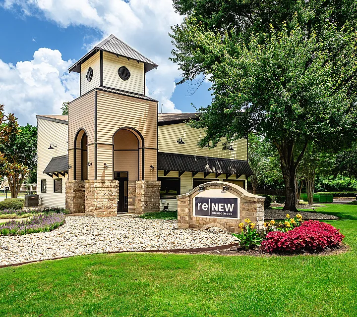 Charming community entrance with a unique clock tower and beautifully landscaped gardens at Renew on Ridgewood.