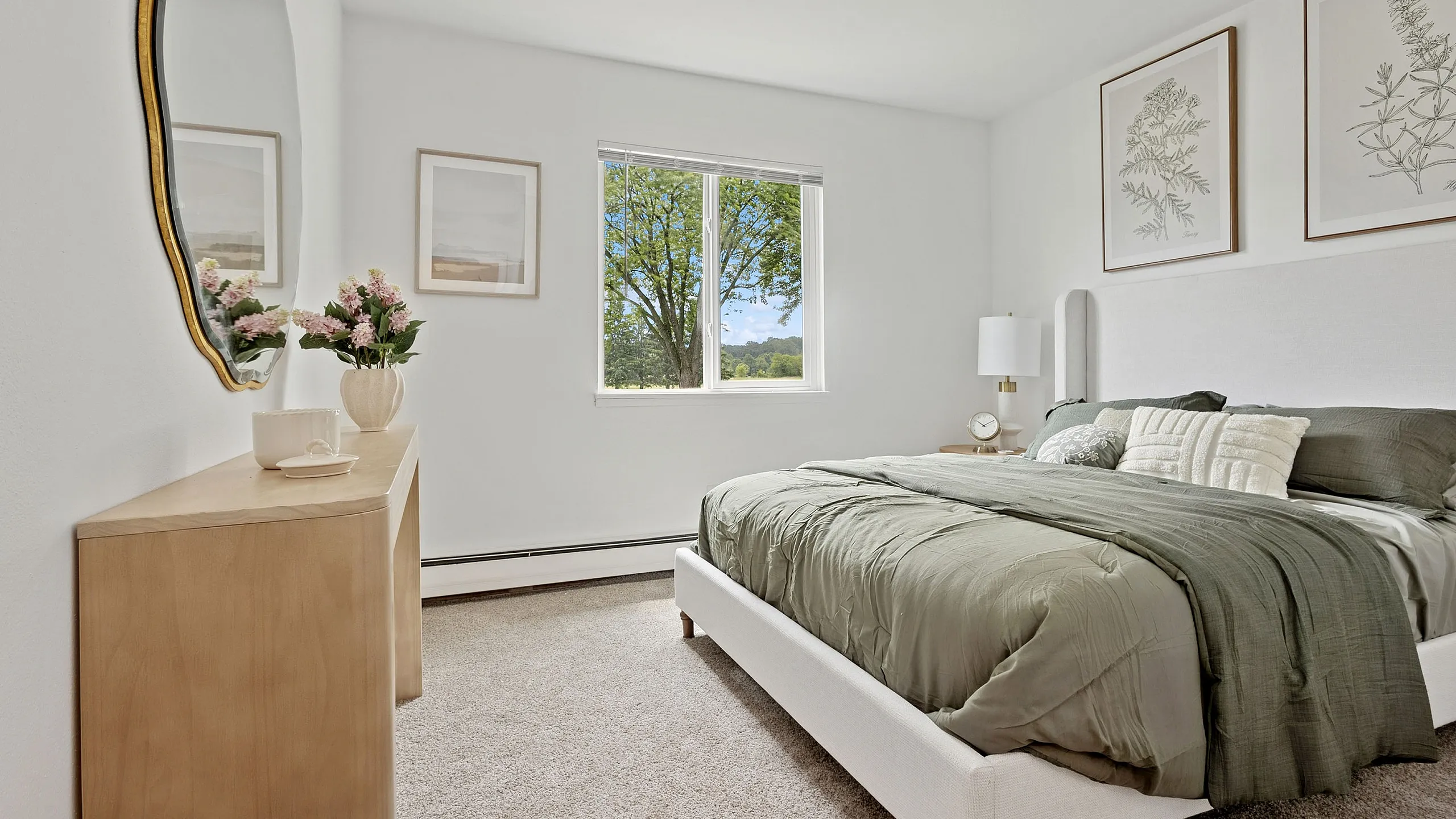 Bright and inviting bedroom with lush green bedding, elegant wall art, and scenic window view, offering a serene living experience.
