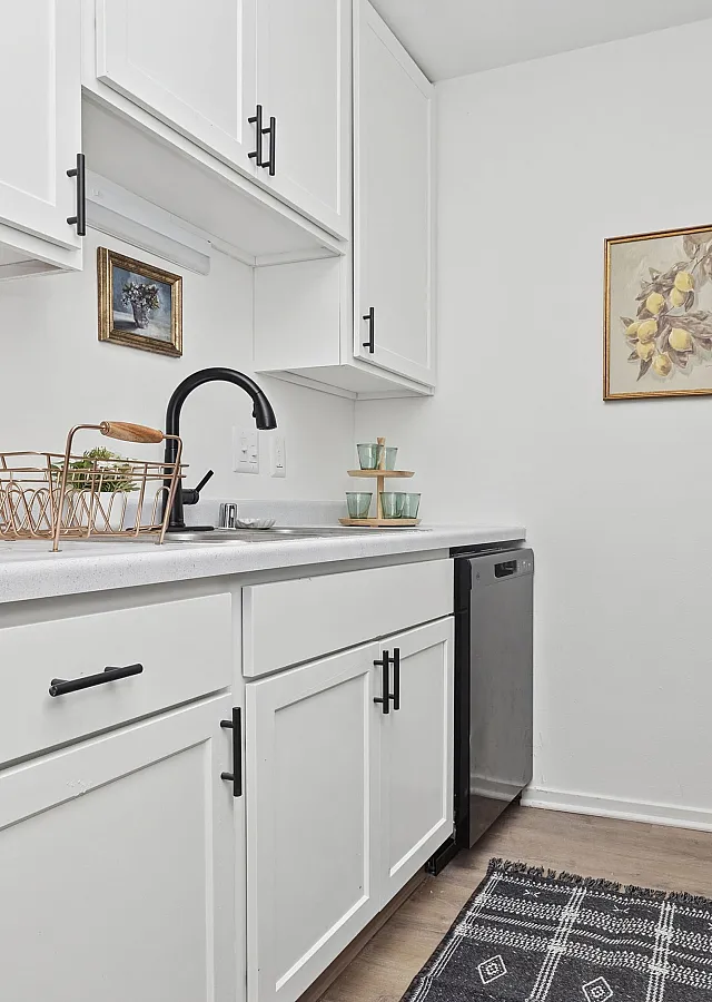 Bright, modern kitchen featuring sleek white cabinets, a stylish black faucet, and contemporary artwork.