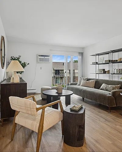 Bright and stylish living room with sleek decor, a large comfortable sofa, and modern furniture, featuring elegant wood flooring and abundant natural light from the sliding balcony doors.