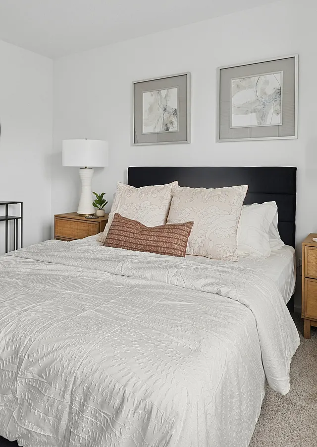 Elegant bedroom featuring a plush bed with stylish pillows, modern bedside tables, chic lamps, and tasteful wall art in a bright, inviting space.