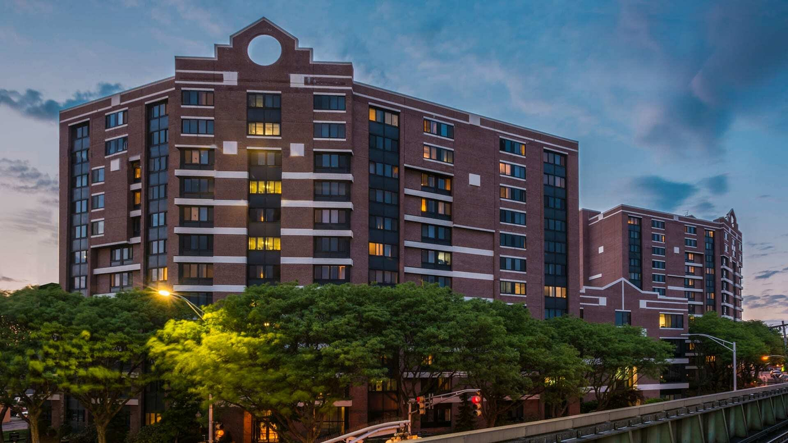 Elegant urban apartment building with unique architectural details, highlighted against a colorful evening sky.