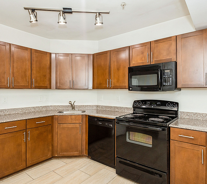 Modern kitchen with rich wooden cabinets, granite countertops, and sleek black appliances.