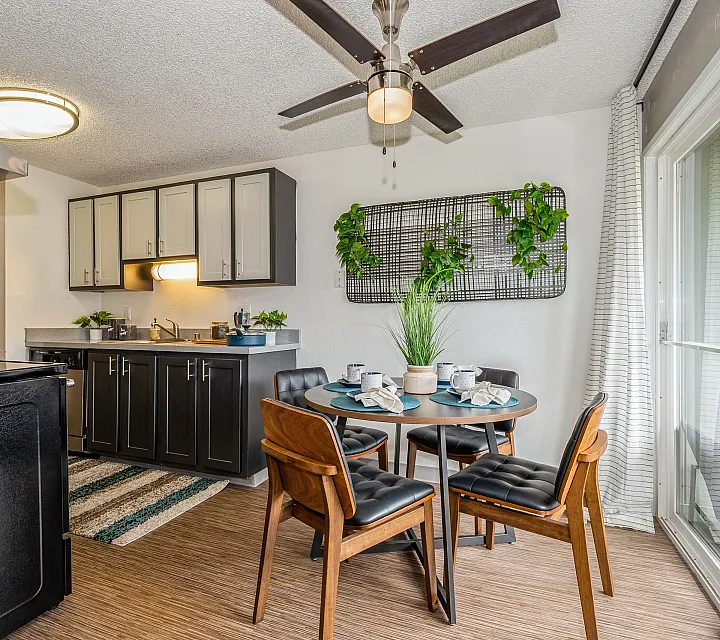 Modern kitchen with stylish cabinets, cozy dining area, and vibrant greenery, offering a warm and inviting atmosphere.
