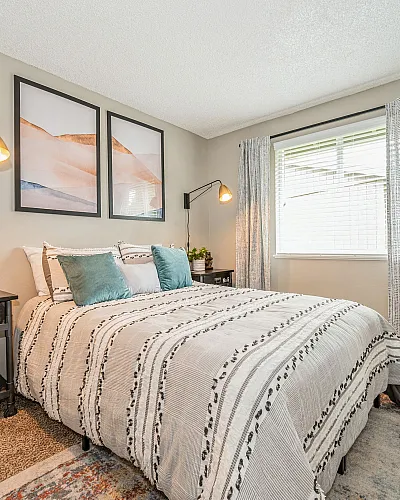 Cozy and stylish bedroom with modern decor, featuring a plush bed, elegant lighting, and a vibrant potted plant by the window.
