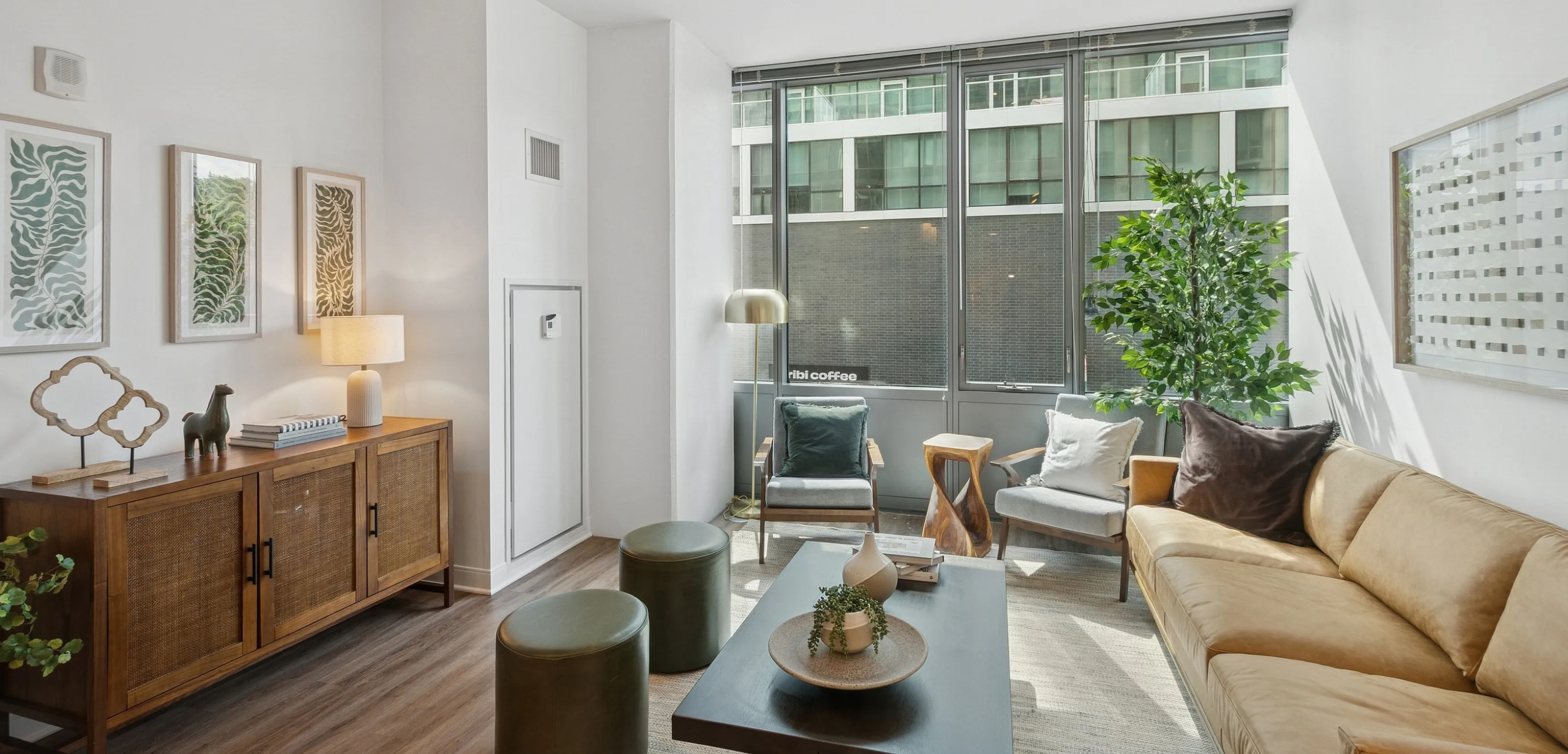 Bright and elegant living room with modern decor, featuring a large window, cozy seating, and stylish wooden furniture.