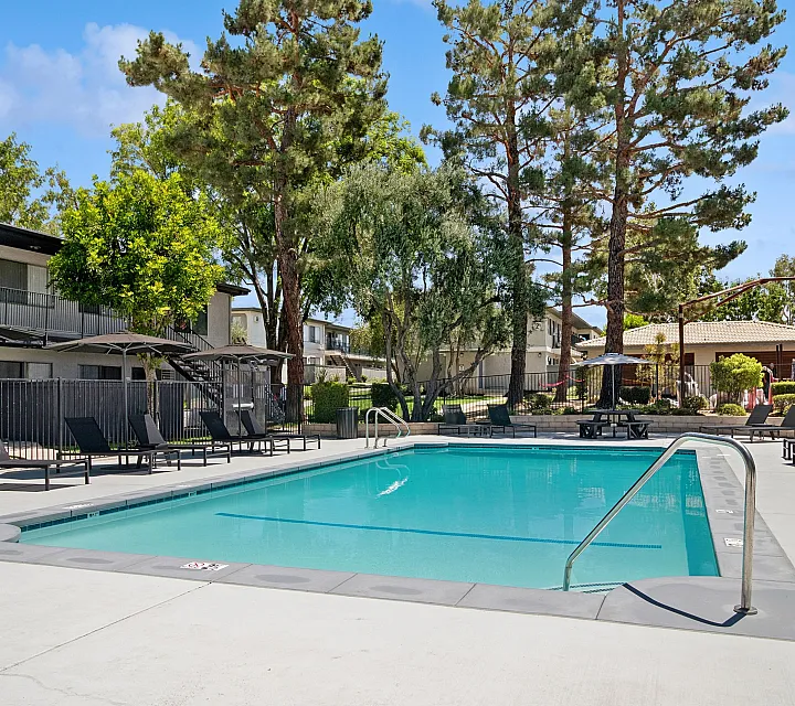 Inviting outdoor luxury pool area surrounded by lush greenery and stylish lounge chairs, perfect for relaxation and leisure.