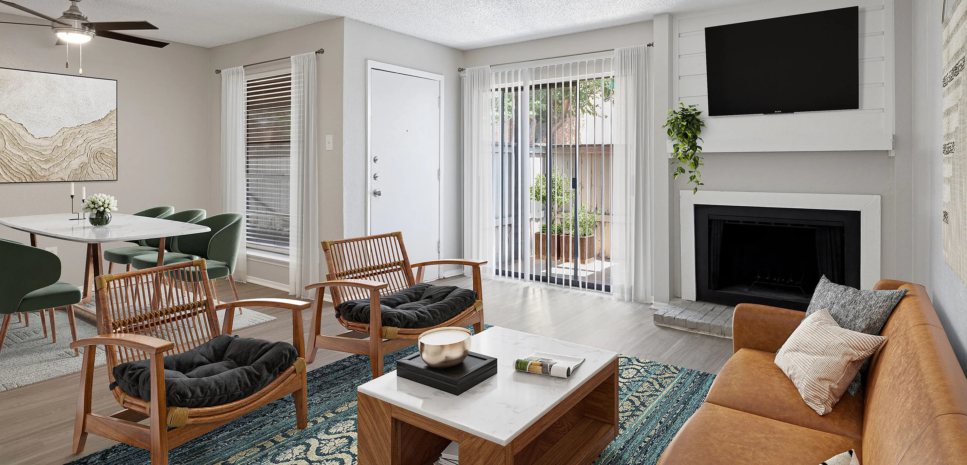 Bright and inviting living room with modern decor, featuring a cozy fireplace, sleek furniture, and a view of the lush outdoor patio through large sliding glass doors.