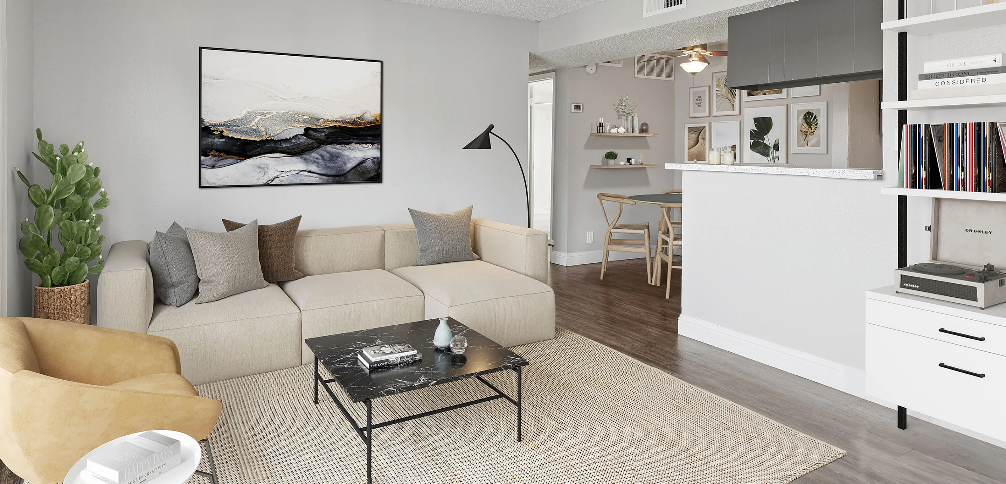 Stylish and modern living room with a cozy beige sectional sofa, vibrant artwork, and an open floor plan leading to a dining area. Perfect blend of comfort and contemporary design.