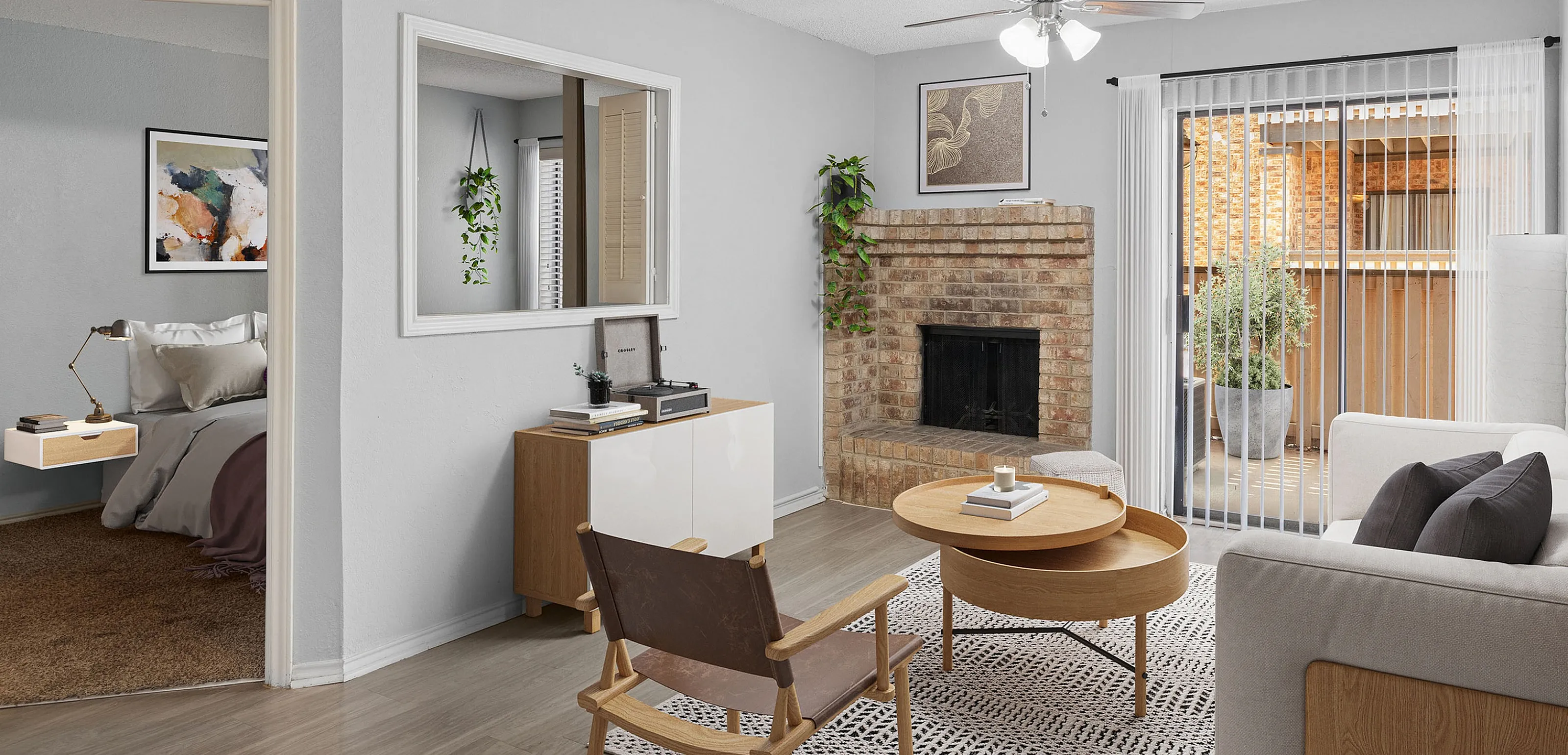 Charming living room featuring cozy brick fireplace, modern furniture, and abundant natural light, with a glimpse into a stylish bedroom.