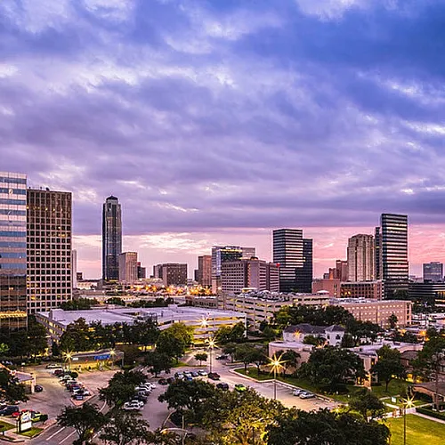 Breathtaking cityscape view showcasing a vibrant skyline at sunset, featuring modern high-rise buildings and lush greenery.