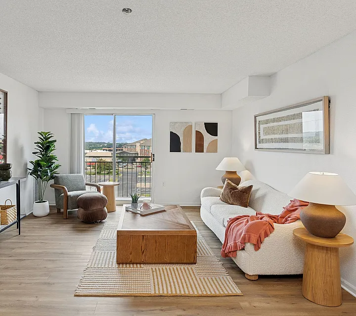 Bright and elegant living room with modern decor, featuring a cozy white sofa, stylish coffee table, and large window with a scenic view.