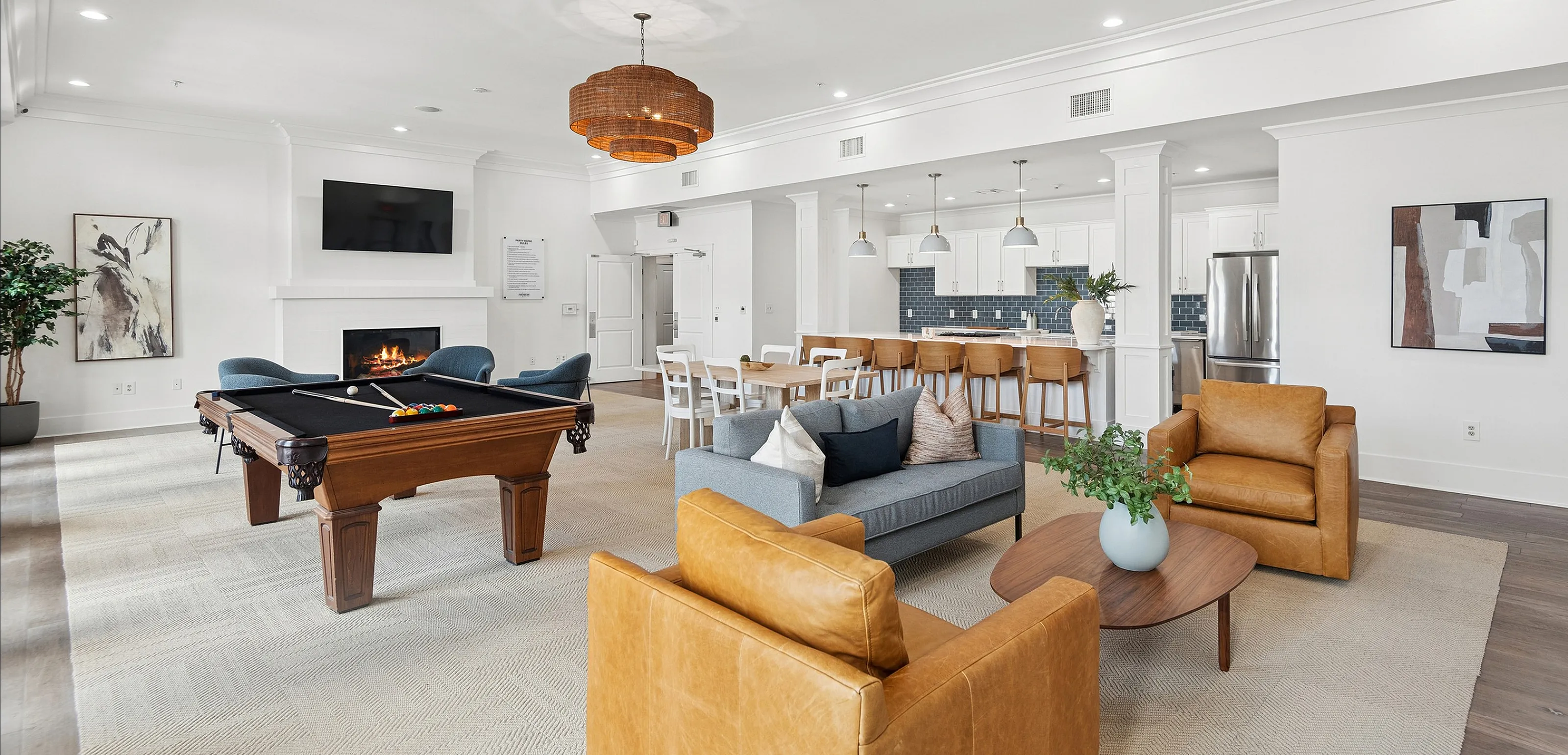 Elegant, open-concept living area featuring a modern kitchen, stylish lounge with a fireplace, and a billiard table for entertainment.