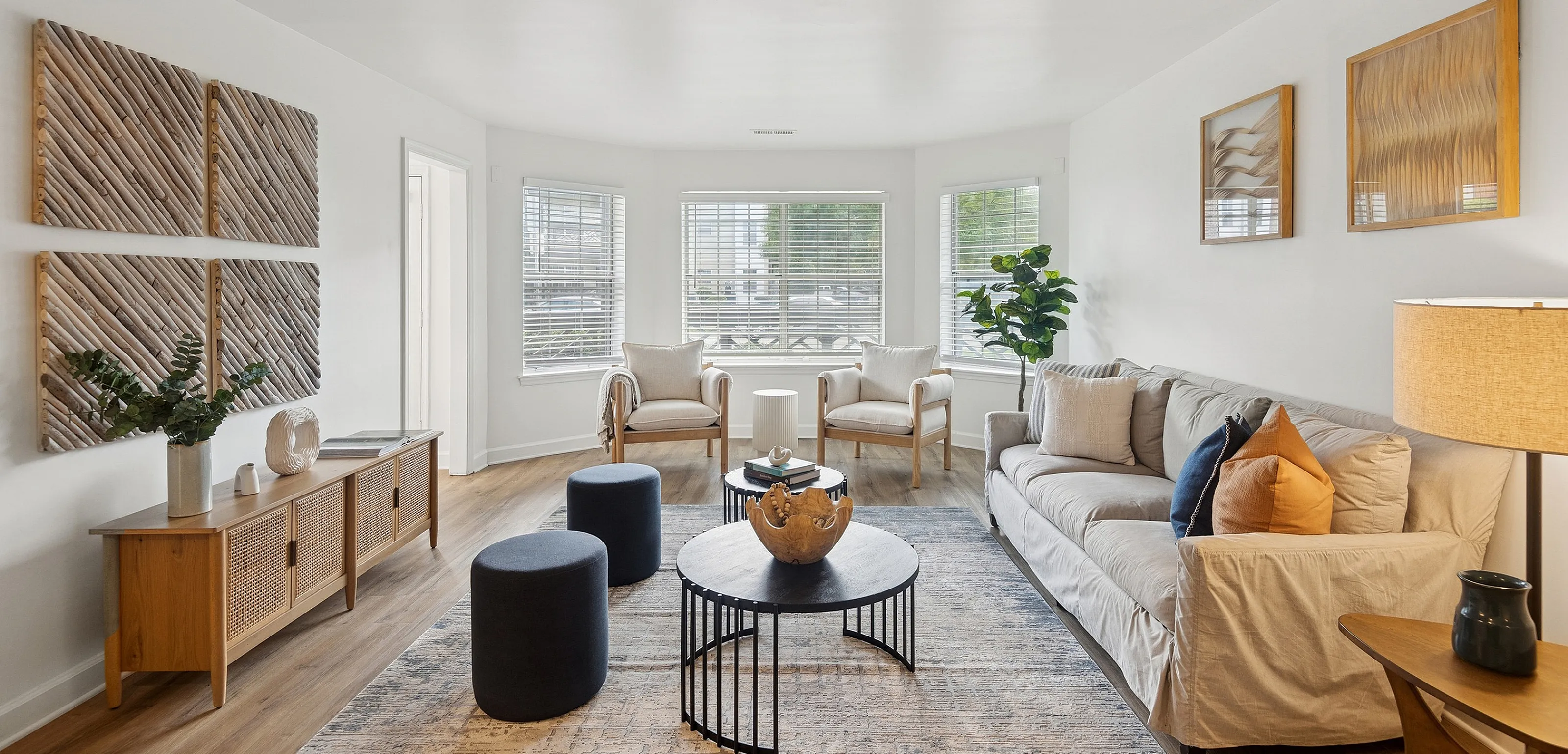 Bright, contemporary living room with stylish decor, featuring a cozy sofa, elegant chairs, and a modern coffee table, illuminated by large windows bringing in abundant natural light.