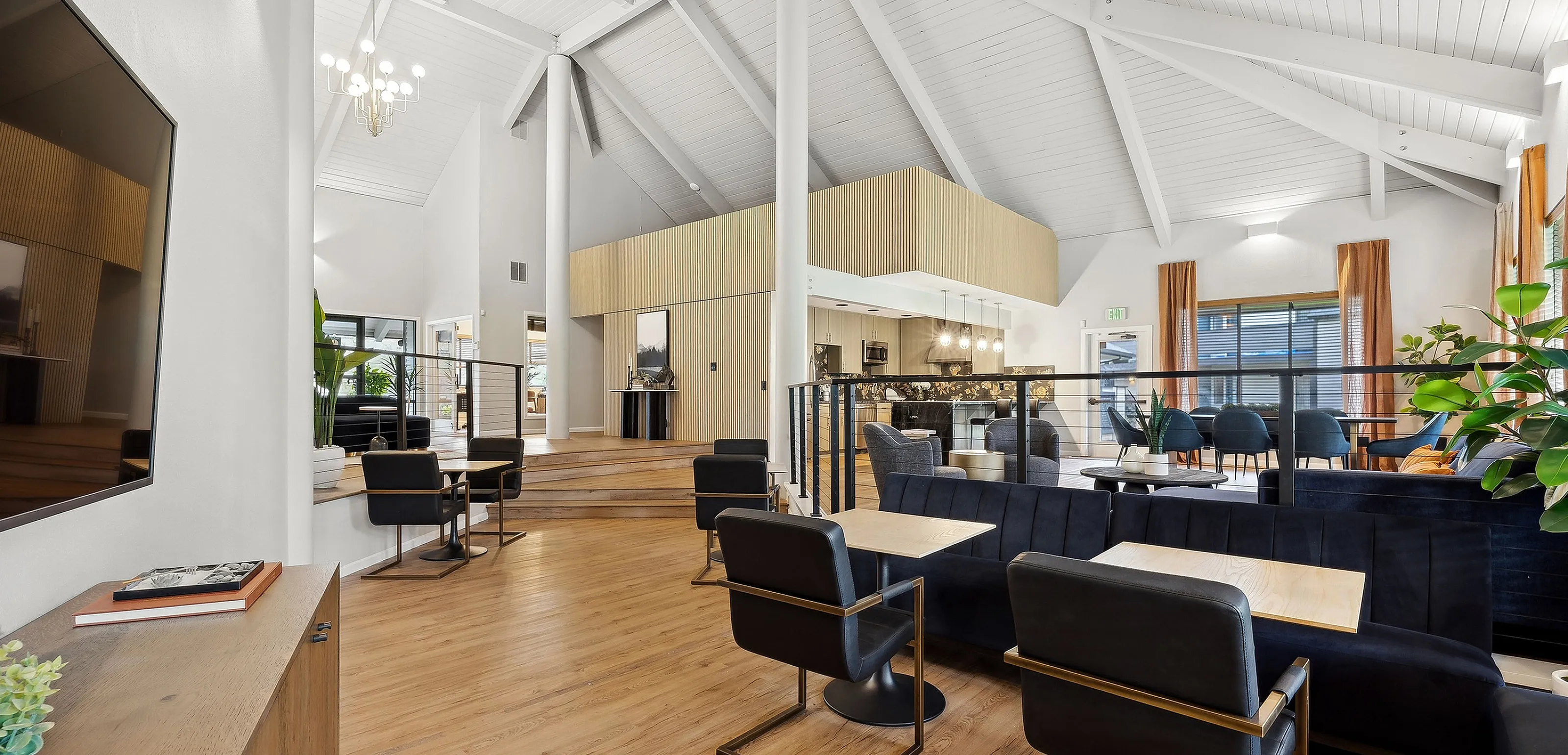 Chic open-concept lounge with vaulted ceilings, elegant lighting, and modern seating in a stylish apartment complex.