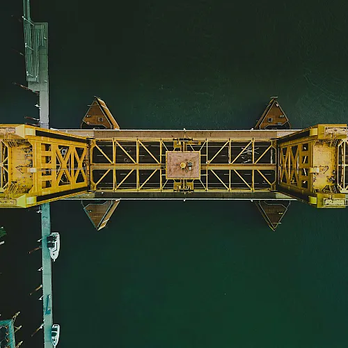 Stunning aerial view of a vibrant yellow drawbridge over a serene river, showcasing architectural elegance and modern engineering.