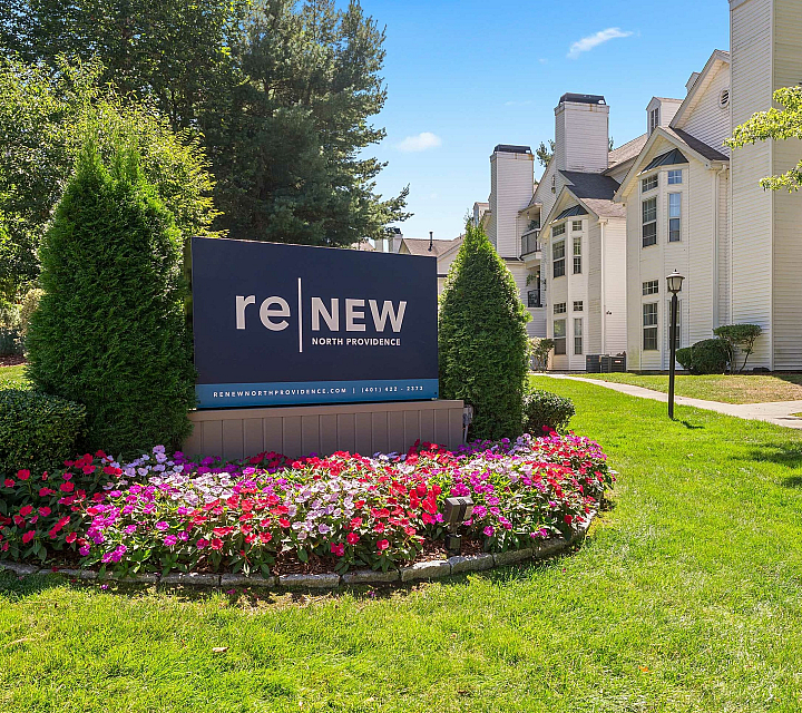 Inviting apartment community entrance with vibrant flowers and stylish architecture at reNEW North Providence.