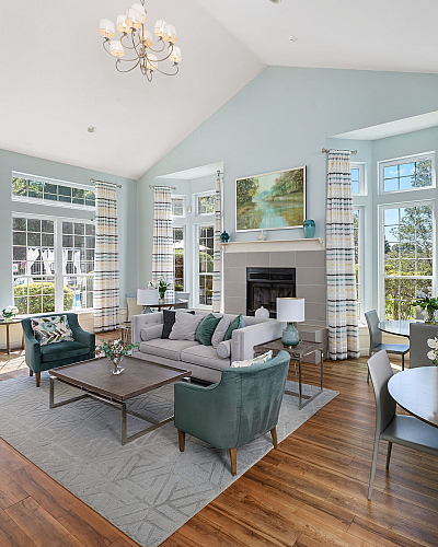 Elegant living room with high ceilings, ample natural light, and modern decor. Features include large windows with pool view, stylish chandelier, cozy fireplace, and wooden flooring. Ideal for modern living and entertaining.