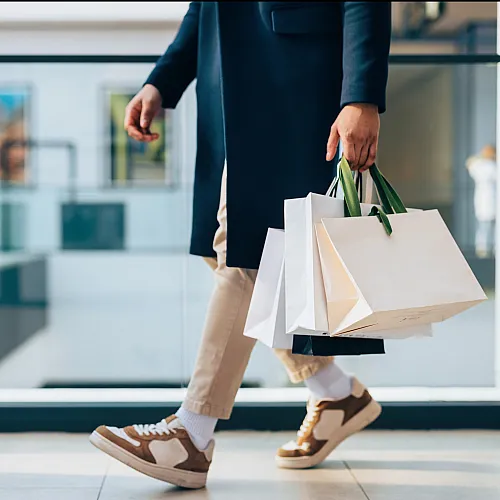 Elegant shopper in a stylish mall carrying multiple luxury shopping bags, showcasing a fashionable lifestyle.
