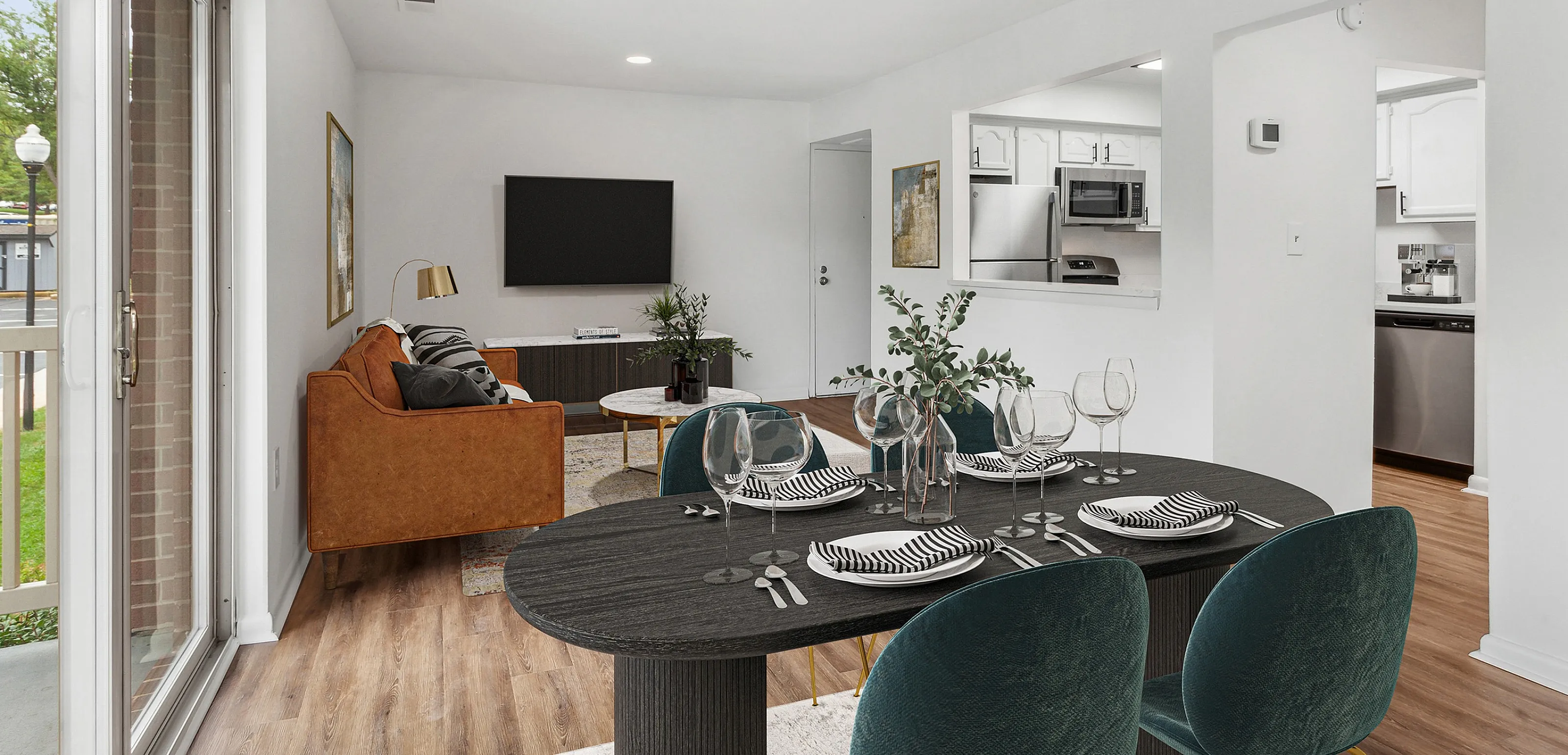 Stylish apartment living area featuring modern dining setup, sleek kitchen, and cozy seating with a view of greenery outside.
