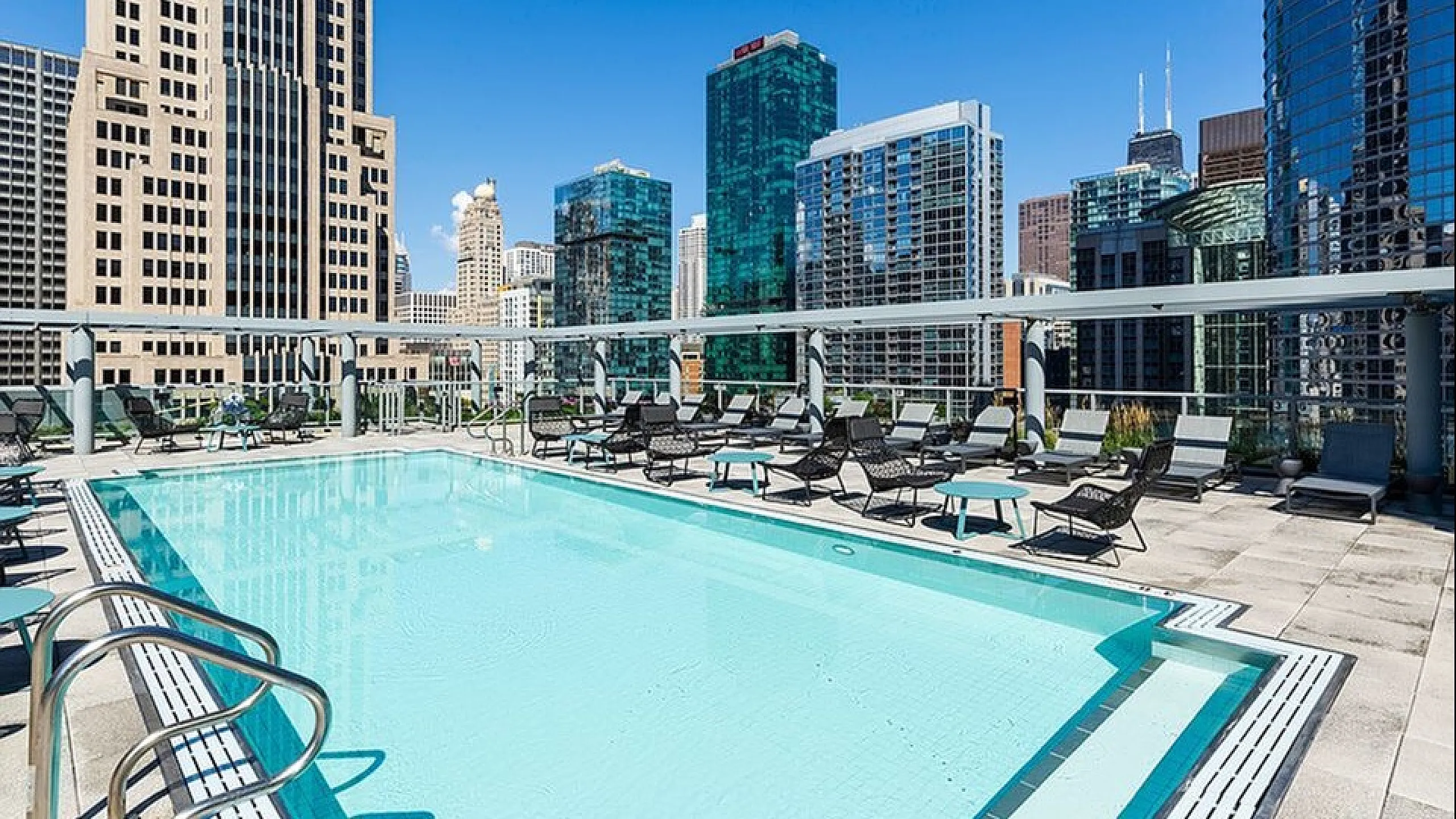 Luxurious rooftop pool with stunning city skyline views and modern lounging area.
