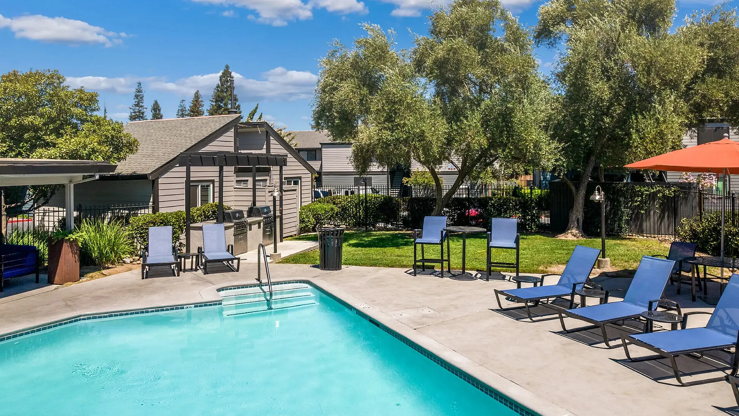 Inviting outdoor pool area with comfortable loungers, shaded seating, and lush greenery, perfect for relaxation and leisure.