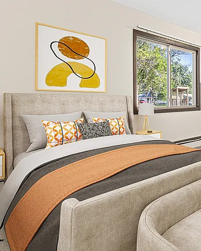 ReNew at the Grove bedroom with modern decor, featuring a plush bed, vibrant abstract art, and a large window illuminating the space with natural light.