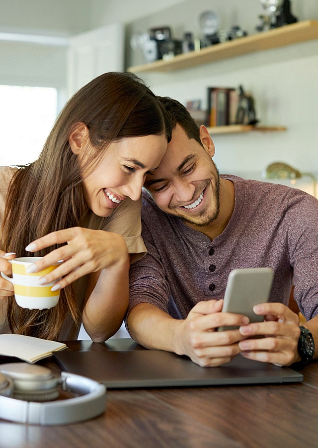 ReNew Meadow Lake happy couple enjoying coffee in a cozy, sunlit living room with modern decor and a warm atmosphere.