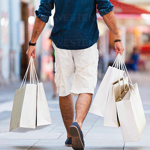 Vibrant shopping scene in a stylish urban setting, featuring people carrying elegant white shopping bags.