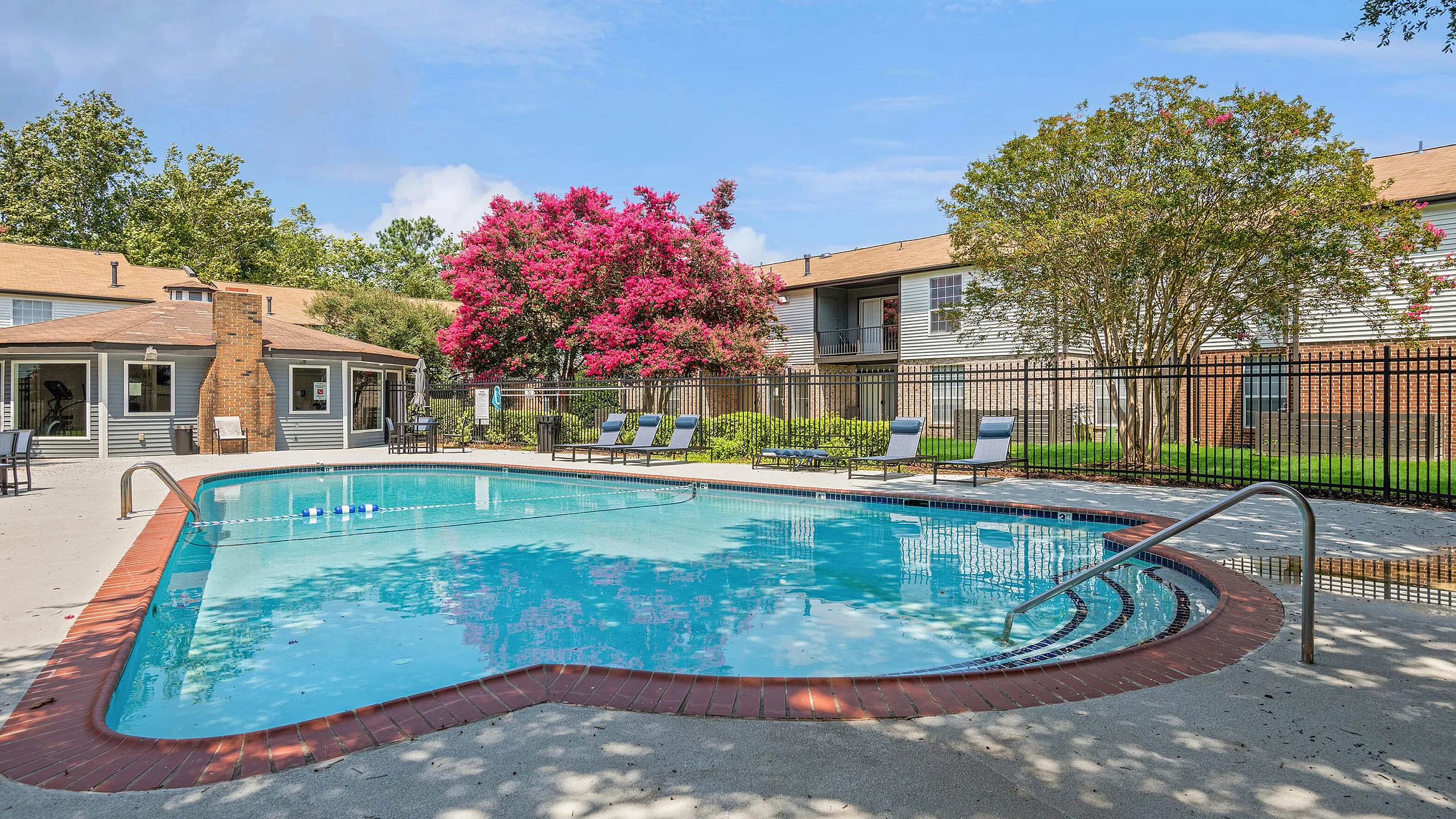 Inviting outdoor pool at ReNew Virginia Beach surrounded by lounge chairs and vibrant landscaping, offering a peaceful retreat in a residential community.