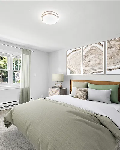 Elegant bedroom featuring a comfortable double bed with green accents, stylish artwork, and a cozy armchair by the sunlit window.