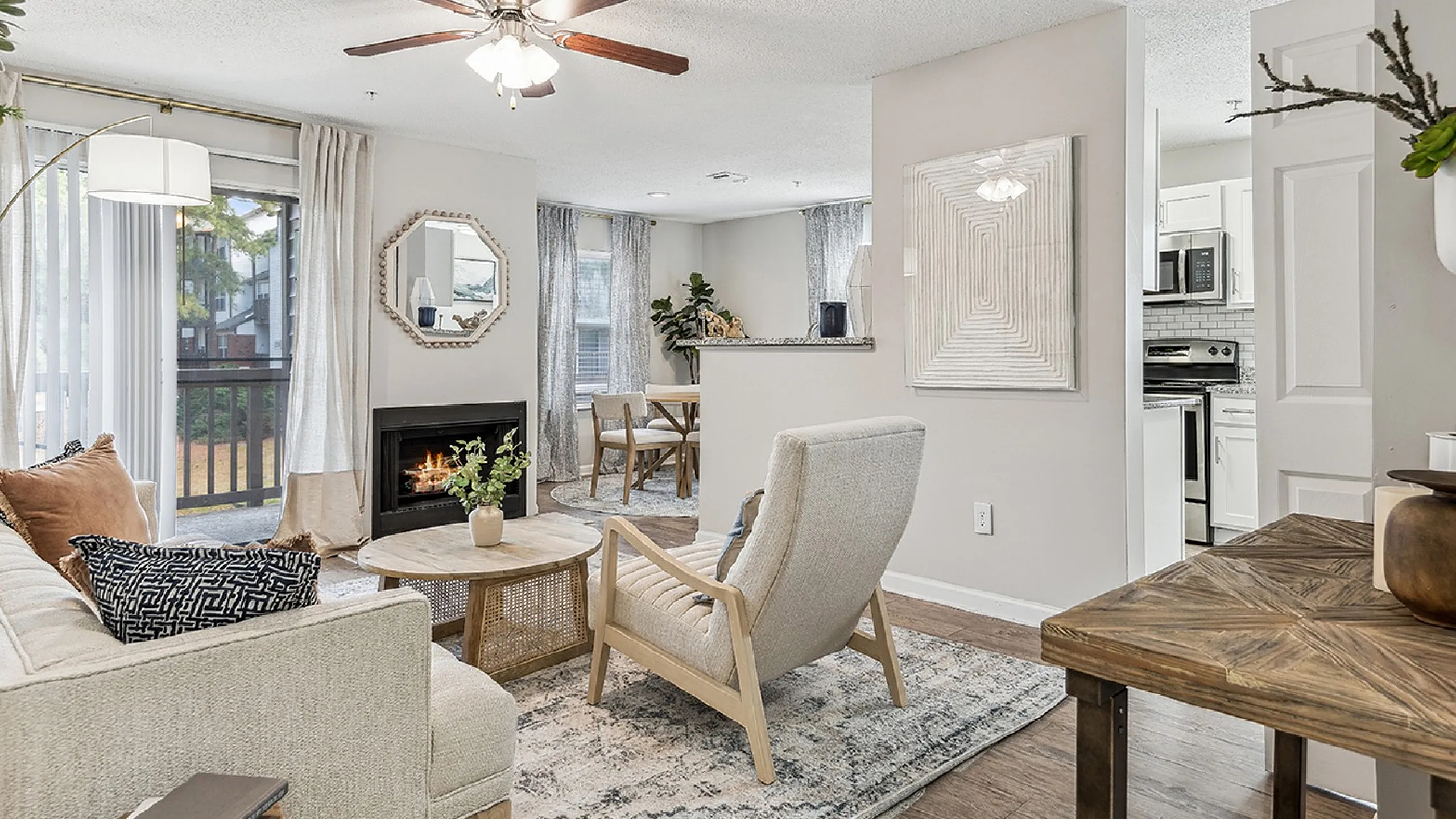 Chic living area at ReNew Marina Shores  with a cozy fireplace, elegant d&eacute;cor, and modern kitchen in the background, bathed in natural light.