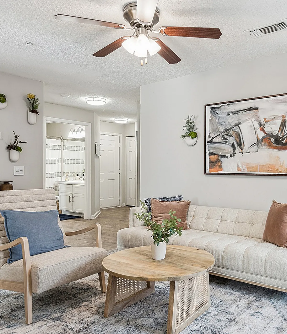 Stylishly designed living room at ReNew Marina Shores  featuring a modern beige sofa, artistic wall decor, and a cozy ambiance with wooden accents and soft lighting.