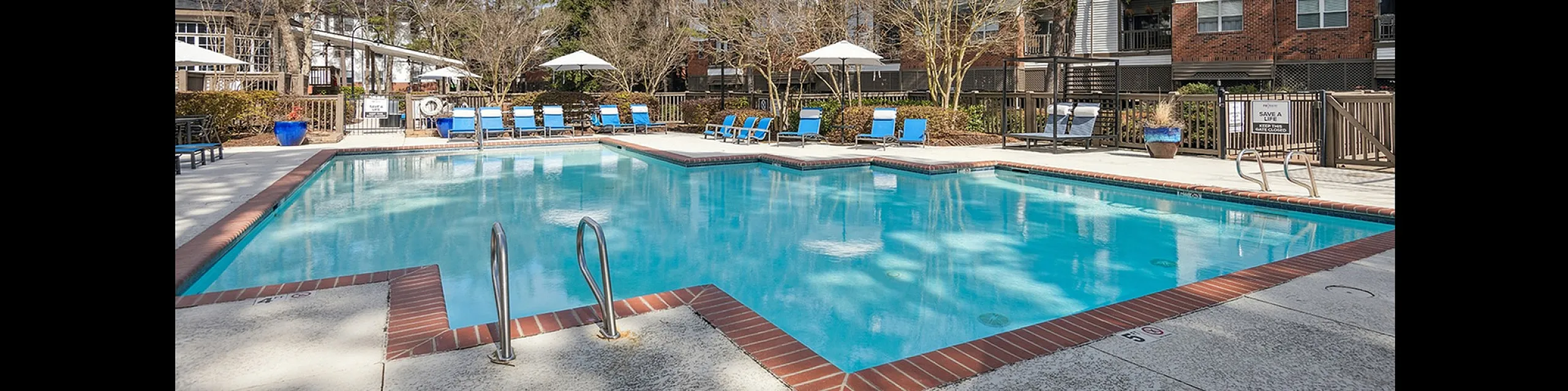 Stunning outdoor pool area at ReNew Marina Shores with clear blue water, surrounded by stylish lounge chairs and lush greenery, offering the perfect spot for relaxation and leisure.