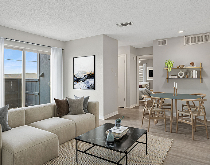 Bright and modern living area at ReNew Midland  featuring a cozy beige sofa, sleek black coffee table, and elegant wall art. Natural light floods through large windows, highlighting the stylish dining set and contemporary decor.