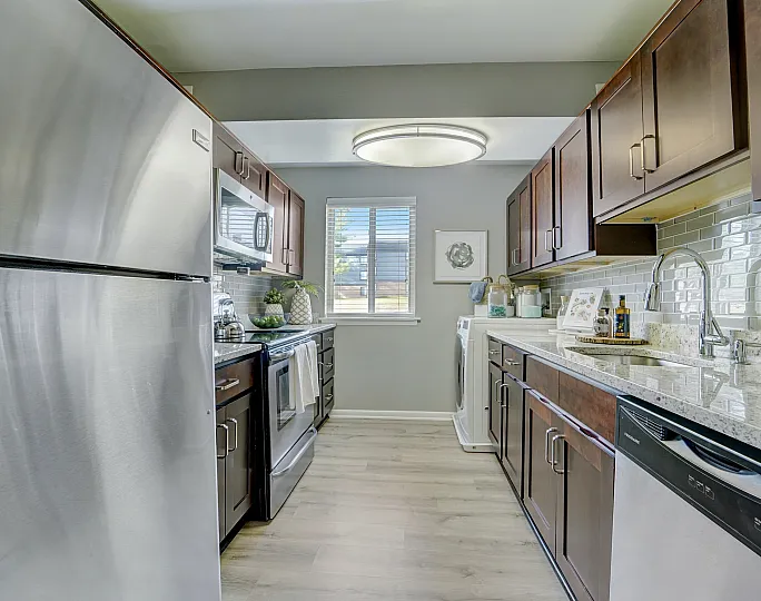 Sleek modern kitchen at ReNew White Marsh with stainless steel appliances, elegant dark wood cabinets, and bright natural lighting.