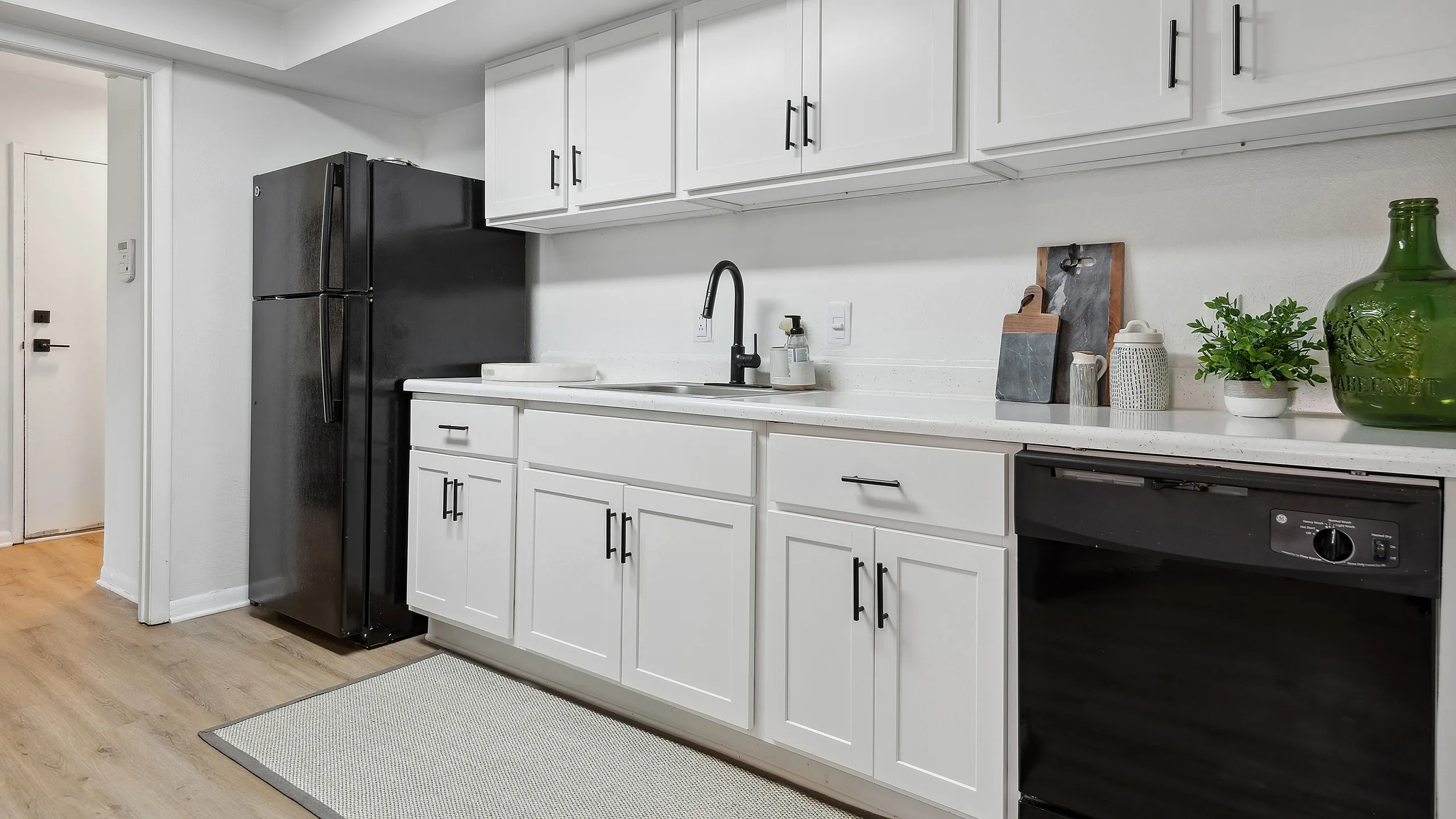 Sleek modern kitchen at ReNew Virginia Beach with white cabinets, spacious countertops, and stylish black appliances.