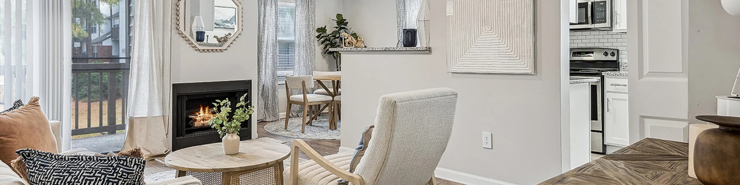 Charming open-concept living space at ReNew Marina Shores  featuring a cozy fireplace, elegant seating, stylish decor, and a modern kitchen.