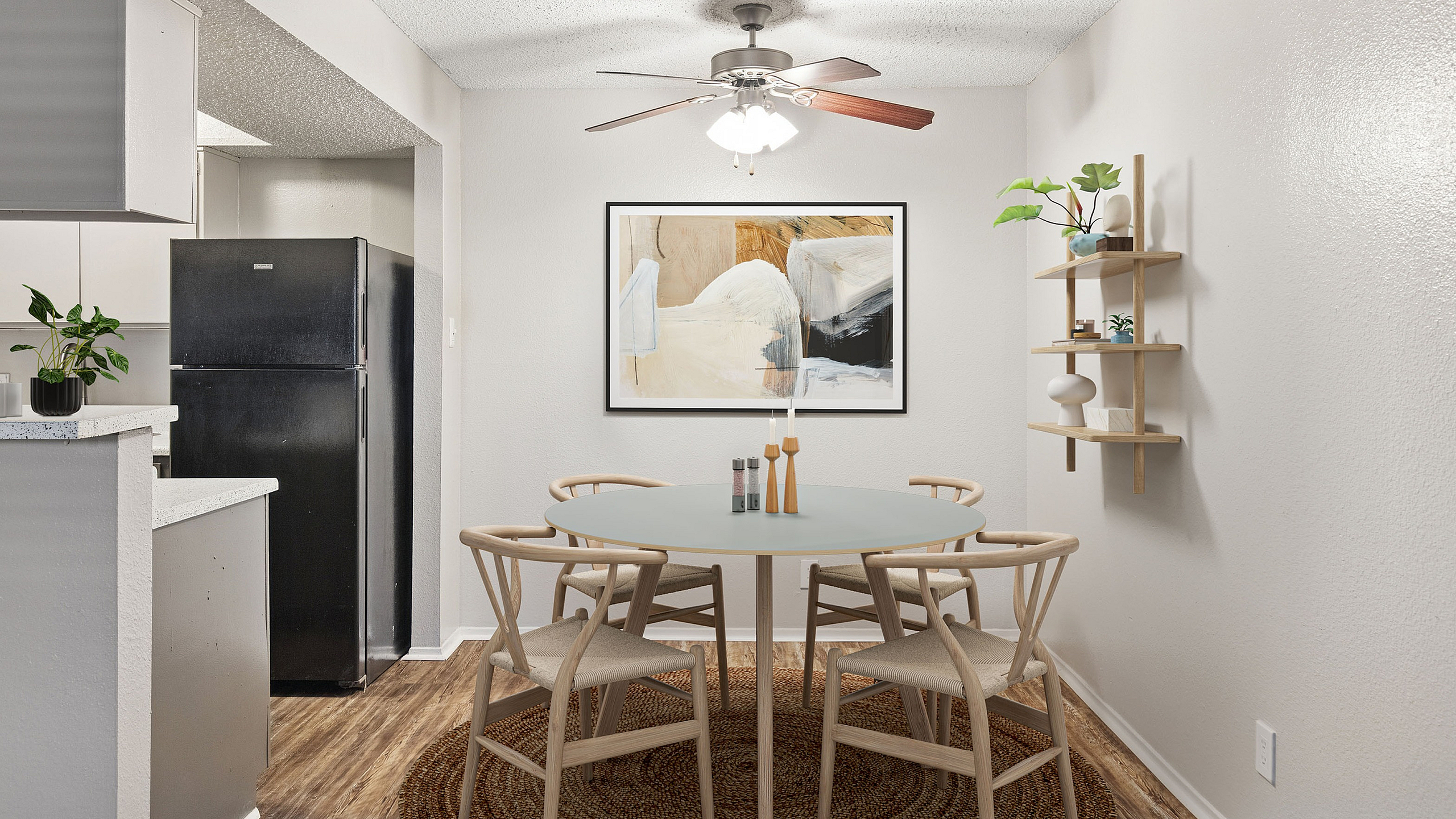Charming dining area at ReNew Heights with modern decor, featuring a round table, elegant wooden chairs, and a stylish ceiling fan, complemented by a chic wall art and open shelving.