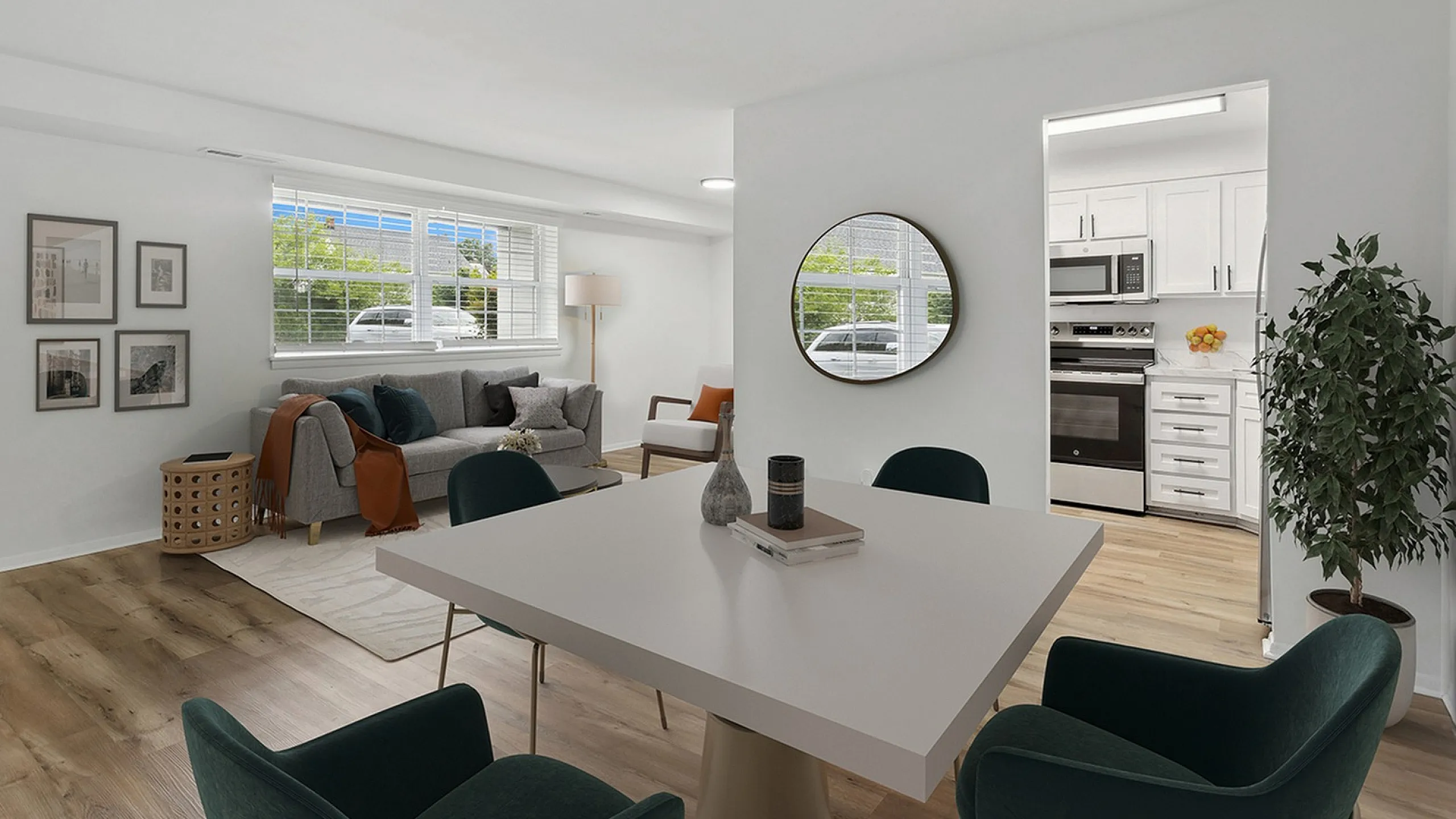 Bright and inviting living space at ReNew Parkville  with contemporary decor, featuring a cozy corner sofa, stylish wall art, and an elegant dining area with a sleek white table. The room seamlessly connects to a modern kitchen with stainle