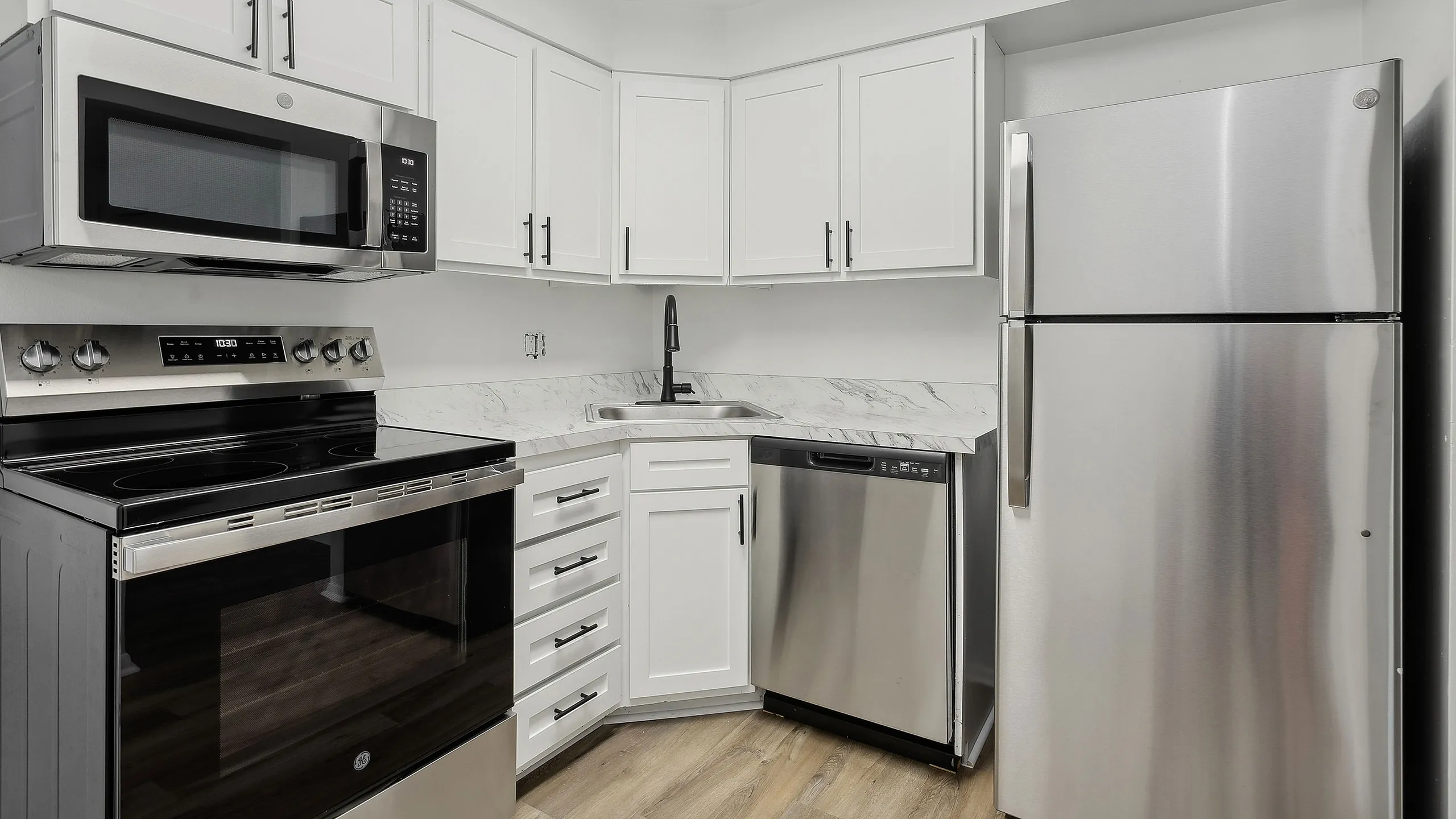 Modern kitchen at ReNew Parkville with sleek stainless steel appliances, white cabinetry, and elegant marble countertops.