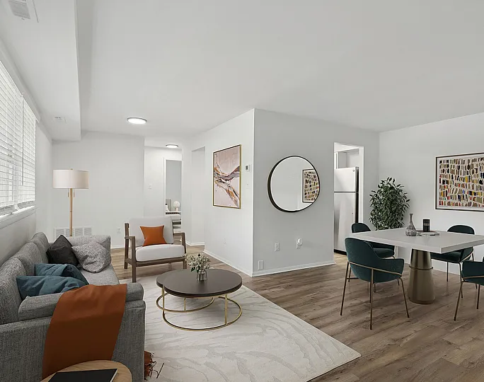 Bright and welcoming open-concept living room and dining area at ReNew Parkville  with modern decor, featuring a cozy gray sofa, elegant dining table, and contemporary artwork on the walls.