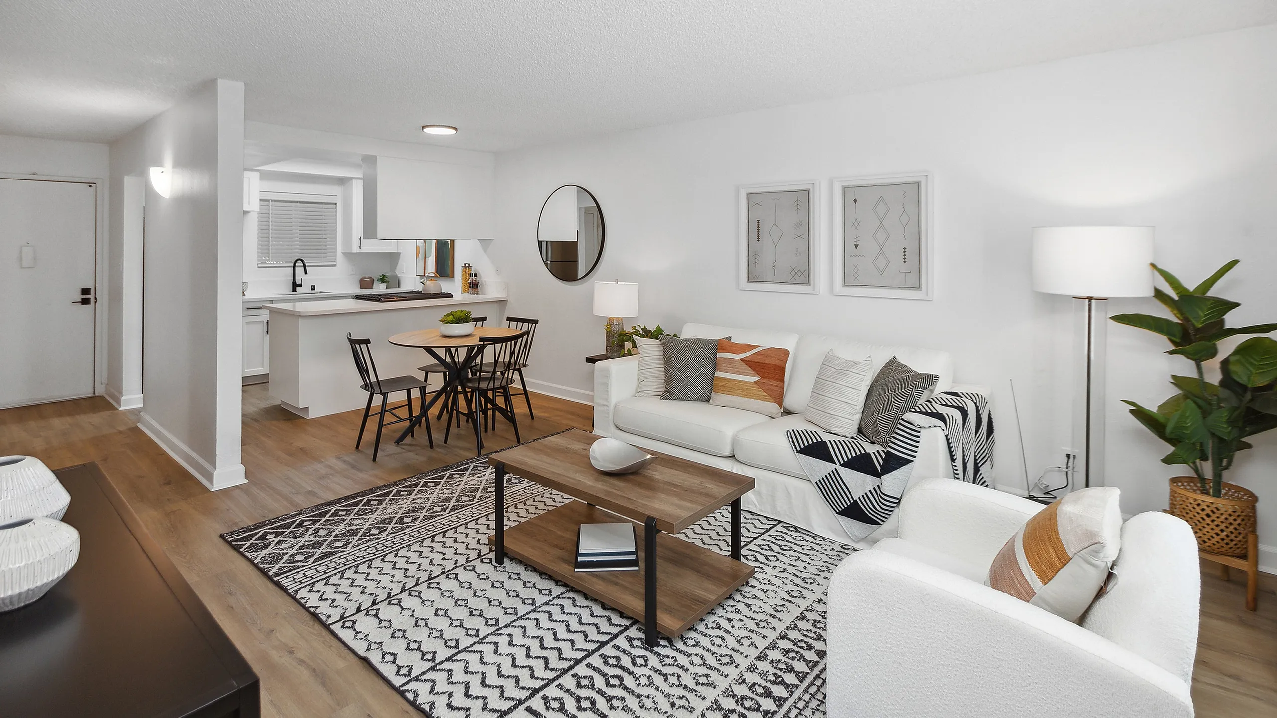 Modern and inviting open-concept living area at ReNew Berryessa featuring cozy seating, wooden dining table, sleek kitchen, and stylish d&eacute;cor accents.