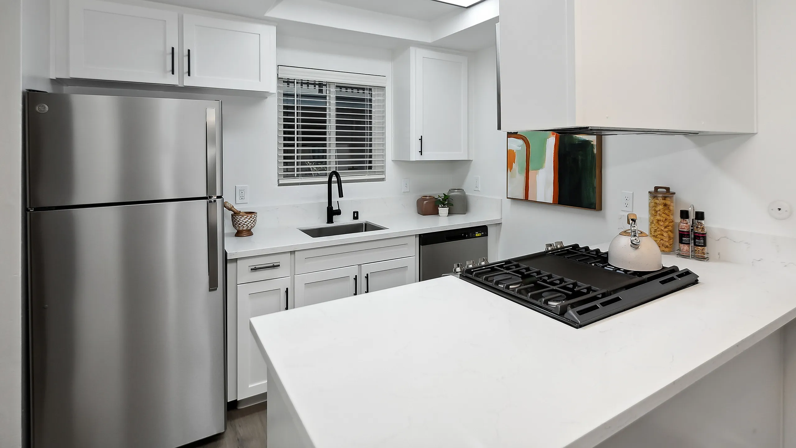 Modern kitchen at ReNew Berryessa with sleek stainless steel appliances, white cabinetry, and a stylish backsplash for a fresh, inviting look.