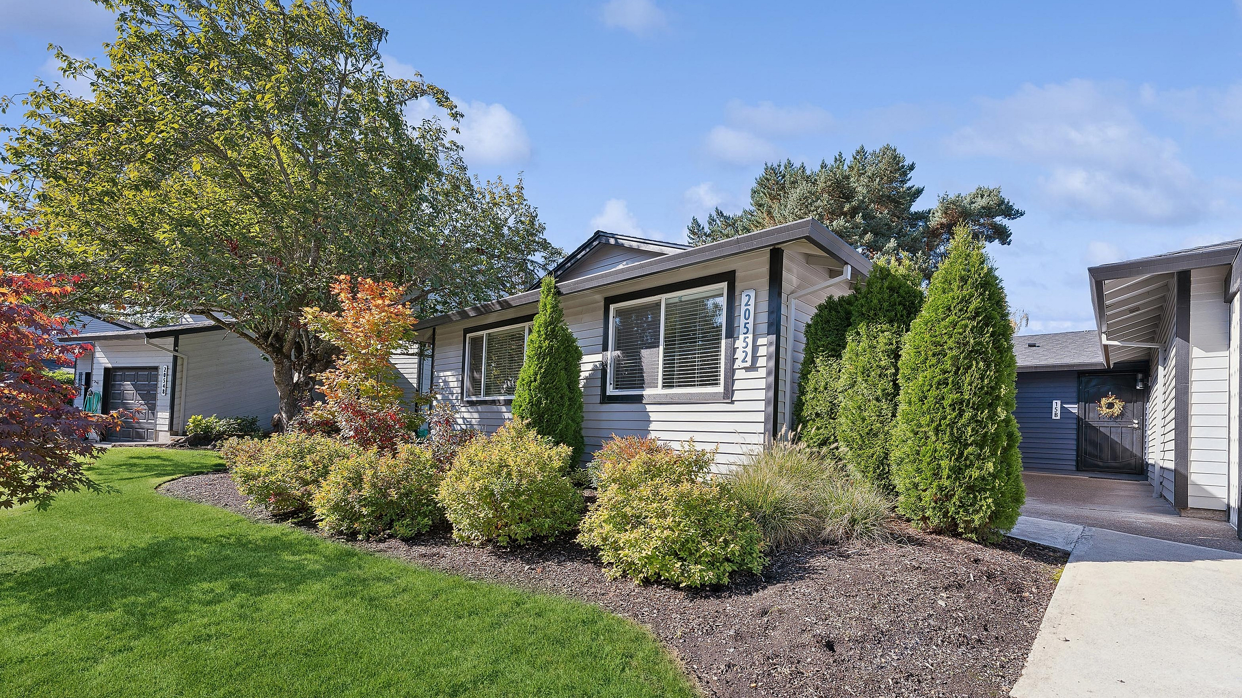 Charming apartment home at ReNew Rock Creek with manicured landscaping, vibrant shrubs, and a welcoming entry in a serene neighborhood.