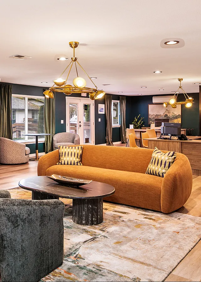Inviting apartment living room with modern furniture, vibrant orange sofa, and elegant lighting, offering a warm and stylish ambiance.