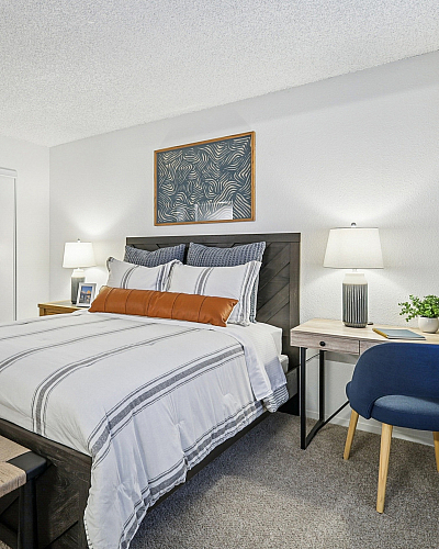 Inviting bedroom with cozy bed, elegant decor, work desk, and ample natural light for a serene atmosphere.