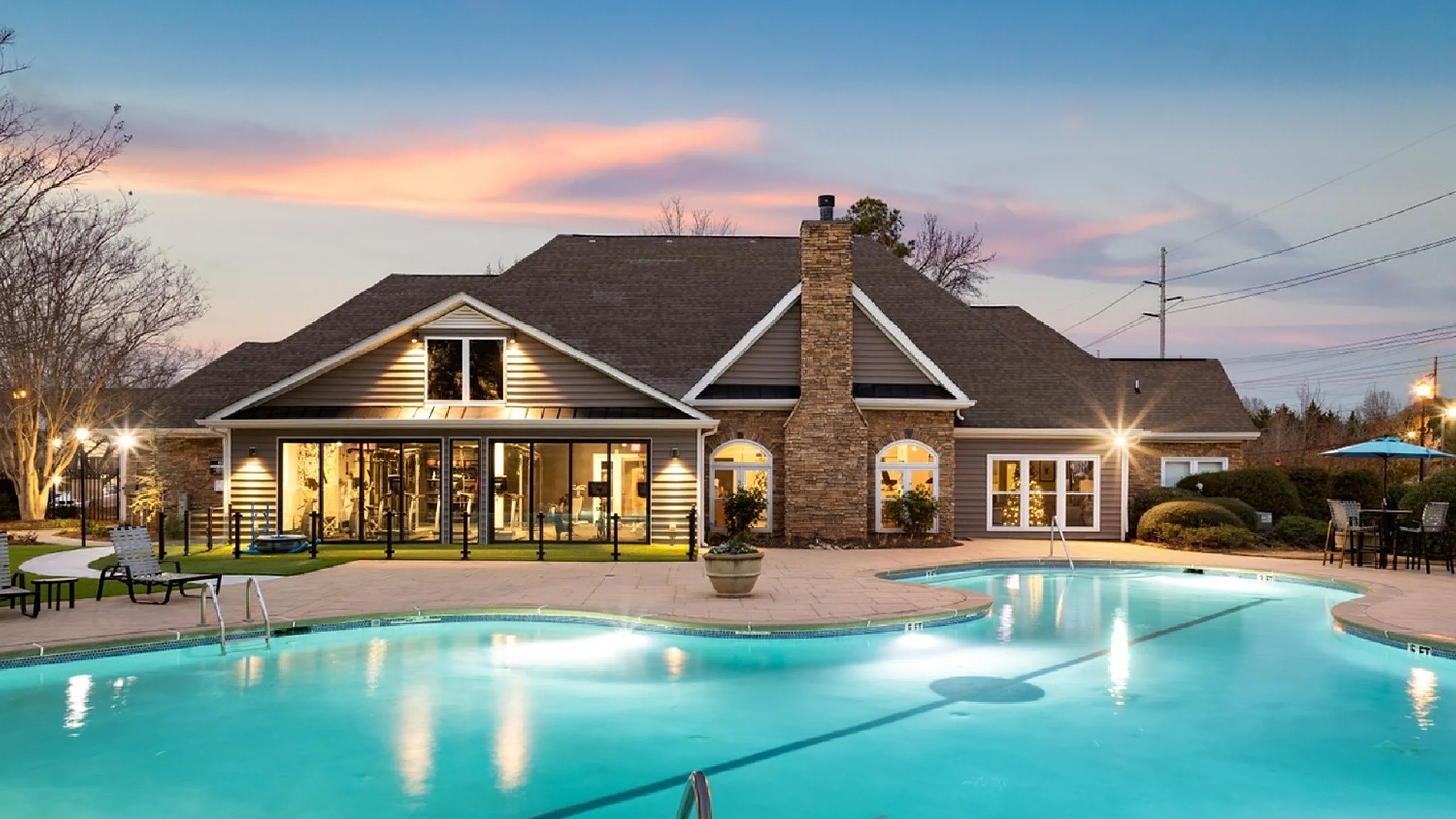 Exquisite apartment clubhouse featuring a stunning outdoor pool at sunset, enhancing luxurious living.
