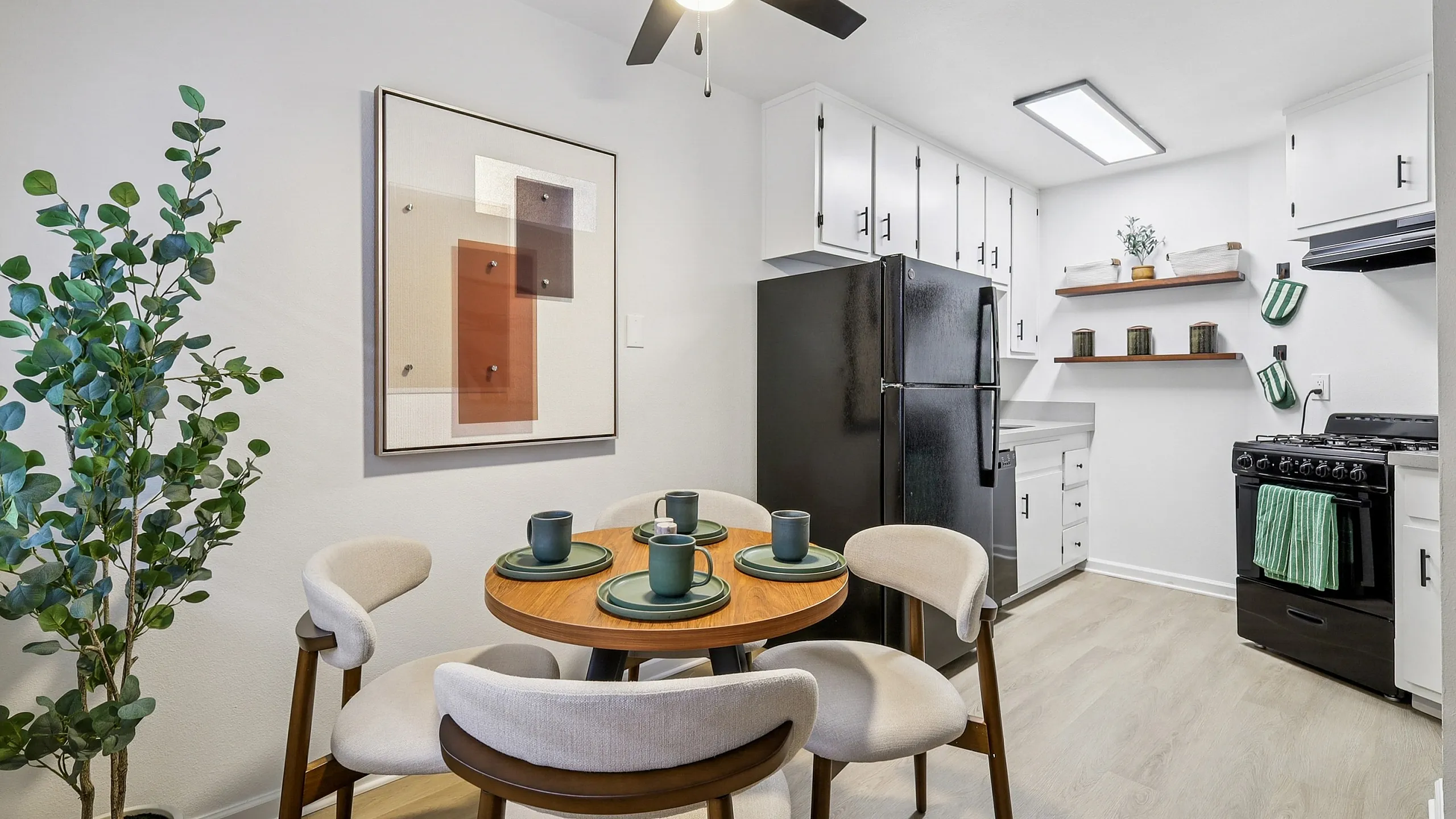 Inviting kitchen-dining area featuring modern black appliances, elegant white cabinetry, and a cozy round dining table set for four.